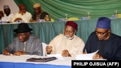 ARCHIVES - (de g. à dr.) Le président nigérian de l'époque, Goodluck Jonathan, le général Abdulsalami Abubakar (ex-chef de l'État), et le candidat à la présidence de l'époque, Mohammadu Buhari, signent un engagement en faveur d'élections apaisées, le 26 mars 2015 à Abuja.