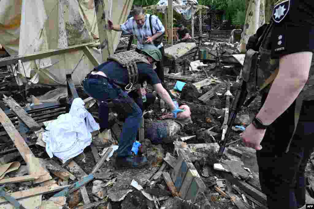 A Ukrainian police officer examines the body of a man who died during missile strikes on a recreation center in Cherkaska Lozova village, near Kharin, amid Russian invasion in UKraine, May 19, 2024.