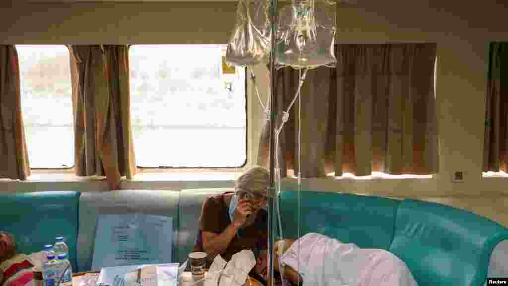 A woman holds the hand of a patient, as patients from the General University Hospital of Alexandroupolis were evacuated in a ferry to escape from a wildfire raging in Alexandroupolis, on the region of Evros, Greece.