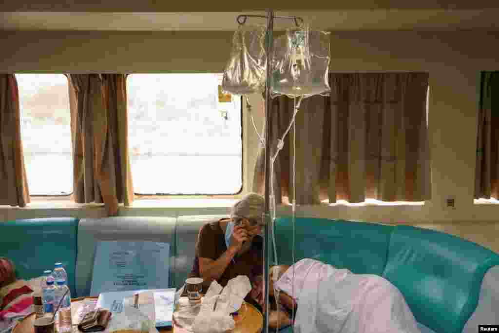 A woman holds the hand of a patient, as patients from the General University Hospital of Alexandroupolis were evacuated in a boat to escape a wildfire burning in Alexandroupolis, Greece.