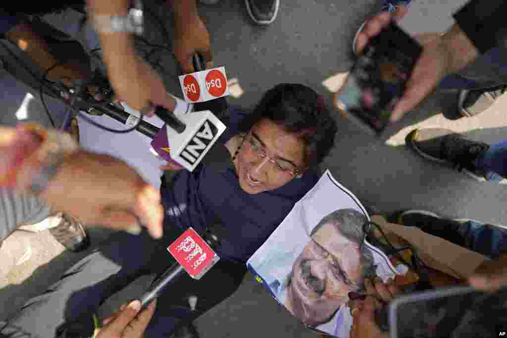 A supporter of Aam Admi Party, or Common Man's Party, shouts slogans as she is detained by police during a protest against the arrest of their party leader Arvind Kejriwal, in New Delhi, India.