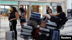 Women stand near their luggage in front of the Middle East Airlines (MEA) offices at the Beirut–Rafic Hariri International Airport, in Beirut, Lebanon, July 28, 2024.