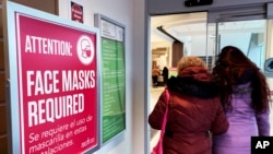 FILE - A sign announcing a face mask requirement is displayed at a hospital in Buffalo Grove, Ill., Jan. 13, 2023. COVID-19 hospital admissions have been inching upward in the U.S. since early July. It's a small-scale echo of the three previous summers.