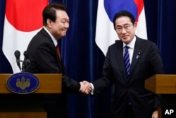 South Korean President Yoon Suk Yeol, left, and Japanese Prime Minister Fumio Kishida, right, shake hands following a joint news conference at the prime minister's official residence in Tokyo, Japan, March 16, 2023.