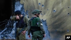 FILE - On Oct. 14, 2023, Israeli soldiers walk past houses destroyed by Hamas militants in Be'eri, Israel, in their Oct. 7 attack on southern Israel. The Israeli military on July 11, 2024, acknowledged errors in its response to the Hamas incursion.