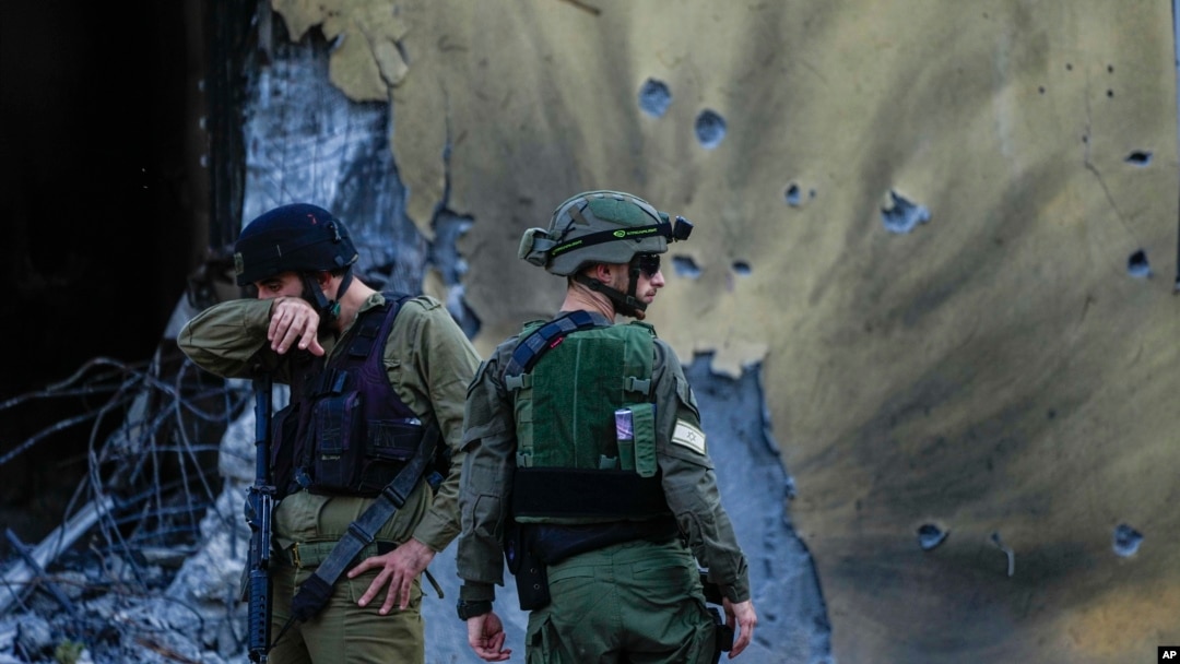 FILE - On Oct. 14, 2023, Israeli soldiers walk past houses destroyed by Hamas in Kibbutz Be'eri, Israel, in the U.S.-designated terror group's Oct. 7, 2023, attack on southern Israel.