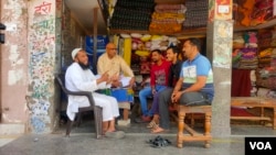 A group of shop owners and residents discuss India's upcoming elections in a market in Muradnagar town in Uttar Pradesh, April 3, 2024. (Anjana Pasricha/VOA)