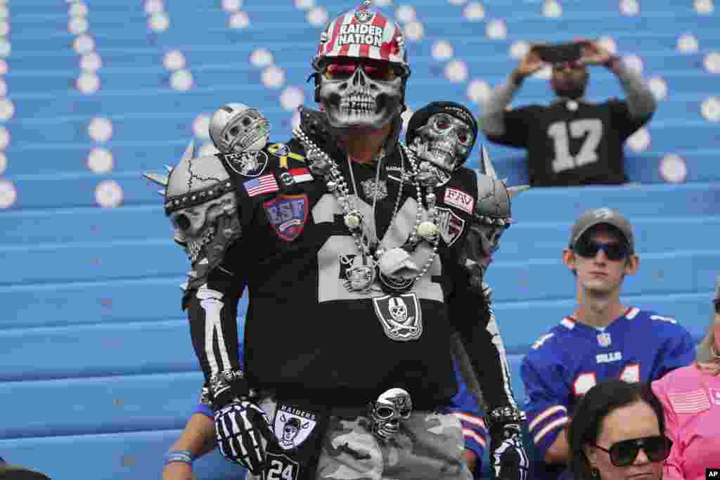 A Las Vegas Raiders fan watches teams warm up before an NFL football game between the Buffalo Bills and the Raiders in Orchard Park, New York.