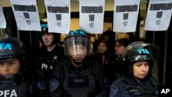 FILE - Police stand guard outside the National Institute against Discrimination, Xenophobia, and Racism, to prevent workers from entering after they were laid off in Buenos Aires, Argentina, April 3, 2024.