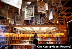 Seorang perempuan membaca buku di bilik Book and Bed, sebuah akomodasi yang dipadukan dengan kafe buku di mana para tamu dapat tidur di Tokyo, Jepang (Foto: REUTERS/Kim Kyung-Hoon)