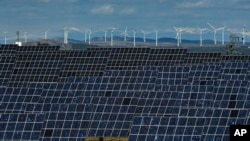 FILE - Solar panels work near the small town of Milagro, Navarra Province, northern Spain, Feb. 24, 2023.