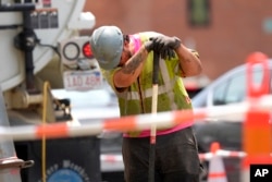 FILE - A worker wipes his face while working in temperatures above 90° F (32° C) at a gas line work site, June 20, 2024, on a street in Boston, Massachusetts.