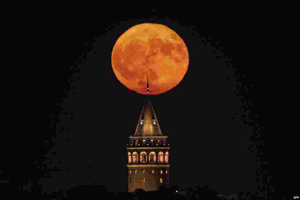 The full moon rises behind the Galata Tower in Istanbul, Turkey, July 21, 2024.