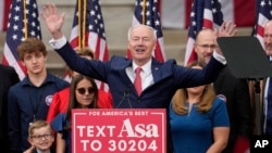 Former Arkansas Gov. Asa Hutchinson is surrounded by family members after formally announcing his Republican campaign for president, April 26, 2023, in Bentonville, Ark.