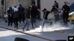 مغربی کنارے کے شہر نابلوس میں ایک فلسطینی احتجاجی، آنسو گیس کےایک گولے کو پاؤں سے ٹھوکر مار رہا ہے۔ 3 اپریل 2023۔
