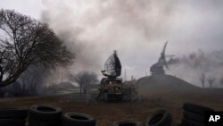 FILE - Smoke rises from an air defense base in the aftermath of an apparent Russian strike in Mariupol, Ukraine, on Feb. 24, 2022. On the battlefields, the fog of war plagues soldiers. The fog of disinformation and misinformation clouds civilians’ understanding of the war.