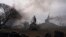 FILE - Smoke rises from an air defense base in the aftermath of an apparent Russian strike in Mariupol, Ukraine, on Feb. 24, 2022. On the battlefields, the fog of war plagues soldiers. The fog of disinformation and misinformation clouds civilians’ understanding of the war.