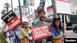 FILE: Oscar-winning directors Daniel Kwan and Daniel Scheinert march with Writers Guild of America members outside Sunset Bronson Studios and Netflix Studios during a strike in Los Angeles, California, on May 3, 2023. Artificial intelligence is part of the labor talks. 