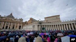 FILE - People crowd St. Peter's Square at the Vatican as Pope Francis delivers his blessing as he recites the Angelus noon prayer from the window of his studio, Feb. 26, 2023.
