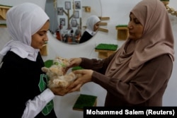 Naeema Mea'bed, perempuan Palestina memegang kucing di "MEOW Cat Cafe" miliknya, di Kota Gaza, 20 Agustus 2023. (Foto: REUTERS/Mohammed Salem)