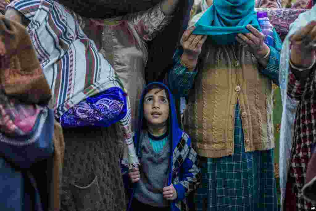 Момче муслиман од Кашмир стои со старешините додека главниот свештеник прикажува света реликвија за која се верува дека е влакно од брадата на пророкот Мухамед во храмот Хазратбал во Сринагар, Кашмир. &nbsp; 