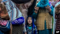 A Kashmiri Muslim boy stands with elders as the head priest displays a holy relic believed to be a hair from the beard of the Prophet Muhammad at Hazratbal shrine in Srinagar, Indian-controlled Kashmir.