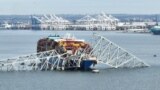 In this aerial image, the steel frame of the Francis Scott Key Bridge sits on top of a container ship after the bridge collapsed, in Baltimore, Maryland, on March 26, 2024. (Photo by Jim WATSON / AFP)