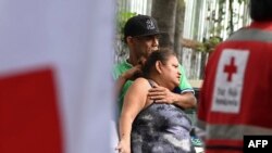 A couple waits for the body of their relative, one of the 46 women killed during a fire following a brawl between inmates of the Women's Social Adaptation Center (CEFAS) prison in Tegucigalpa, Honduras, on June 21, 2023. 
