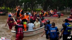 Warga mengungsi dengan perahu akibat banjir di Zhuozhou di provinsi Hebei, China utara, selatan Beijing, Rabu, 2 Agustus 2023. (AP/Andy Wong)