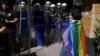 FILE - An activist stands near riot police who prevent activists from marching in a pride parade, which was banned by local authorities, in central Istanbul, June 26, 2022.