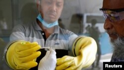 বাংলাদেশেের ঢাকার মুগদা মেডিকেল কলেজ ও হাসপাতালে করোনভাইরাস পরীক্ষার জন্য একজন ব্যক্তির থেকে সোয়াব সংগ্রহ করছেন একজন স্বাস্থ্যকর্মী। ২ জুলাই, ২০২০। (ফাইল ছবি) 