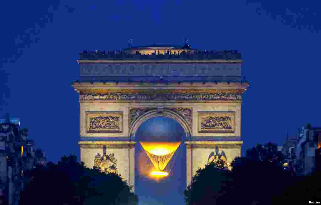 Kaldron (cauldron) Olimpiade dan monumen Arc de Triomphe terlihat setelah matahari terbenam selama Olimpiade di Paris, Prancis. (Reuters)&nbsp;