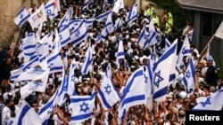 Israelis sing and dance with flags by Damascus gate to Jerusalem's Old City as they mark Jerusalem Day, in Jerusalem, May 18, 2023.