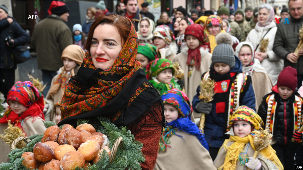 Desde Ucrania: Una mujer camina por las calles cargando donas tradicionales mientras participa en la celebración de Nochebuena en Leópolis, el 24 de diciembre de 2023, en medio de la invasión rusa de Ucrania.