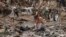 A man washes his clothes in a stream near debris left over after flooding devastated the village of Nanxinfang on the outskirts of Beijing on Aug. 4, 2023. 