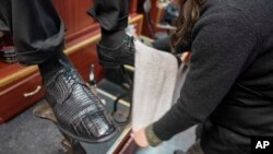 Bertha Gomez menyemir sepatu pelanggan di Alpha Shoe Repair Corp. di New York, 3 Februari 2023. (AP/Mary Altaffer)