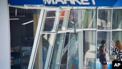 In this photo released by the Dnipro Regional Administration, people stand near shop windows damaged following Russia's missile attack in Dnipro, Ukraine, July 3, 2024.