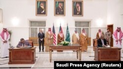 FILE — Saudi Foreign Minister Prince Faisal bin Farhan bin Abdullah Al-Saud stands along with SAF and RSF representatives as they sign an agreement for a seven-day cease-fire, May 20, 2023.