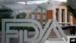 FILE - A U.S. Food and Drug Administration building is seen behind FDA logos in Silver Spring, Maryland, Aug. 2, 2018.