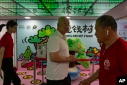 Visitors to a shopping mall walk past a promotion to give away vouchers at a shopping mall in Beijing, July 25, 2024.