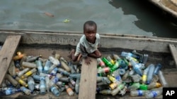 FILE - A child in a canoe with plastic bottles for recycling in Lagos, Nigeria, Nov. 8, 2022. Negotiators at UNESCO in Paris for talks on global treaty to fight plastic pollution. 