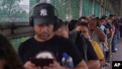 Residentes provenientes de Matamoros, México, se paran en el puente de Puerto Nuevo mientras esperan su turno para cruzar legalmente la frontera hacia Brownsville, Texas, la madrugada del viernes 12 de mayo de 2023. (Foto AP/Fernando Llano)