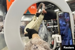 A host promotes a bag during a live streaming session at a warehouse of second-hand luxury e-commerce platform ZZER in Shanghai, China July 5, 2023. (REUTERS/Xihao Jiang)