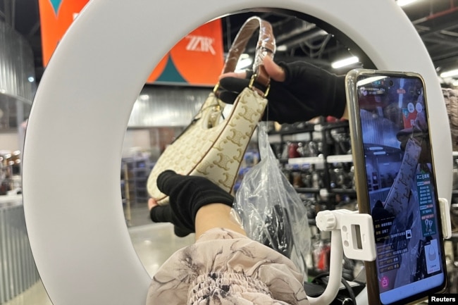 A host promotes a bag during a live streaming session at a warehouse of second-hand luxury e-commerce platform ZZER in Shanghai, China July 5, 2023. (REUTERS/Xihao Jiang)