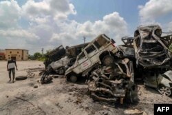 A man walks past burned vehicles after violent communal clashes in Nuh, India, Aug. 1, 2023.