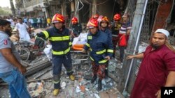 Firefighters move the body of a victim after an explosion in a building in Dhaka, Bangladesh, March 7, 2023. 