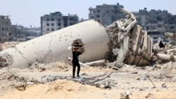 A Palestinian child transporting pieces of wood walks past a building destroyed by Israeli bombardment in Gaza City on May 3, 2024.