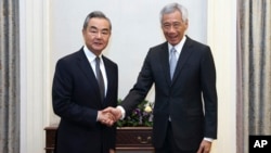 资料照片: 2023年8月11日中国外长王毅(左)与新加坡总理李显龙握手