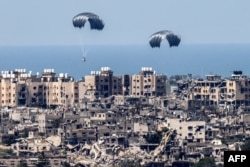 This picture taken from Israel's southern border with the Gaza Strip shows parachutes of humanitarian aid dropping over the besieged Palestinian territory on March 26, 2024, amid the ongoing conflict between Israel and the militant group Hamas.