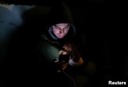 A local resident takes cover with his dog in a parking lot near an apartment building damaged during a Russian drone strike, amid Russia's attack on Ukraine, in Kyiv, Dec. 22, 2023.